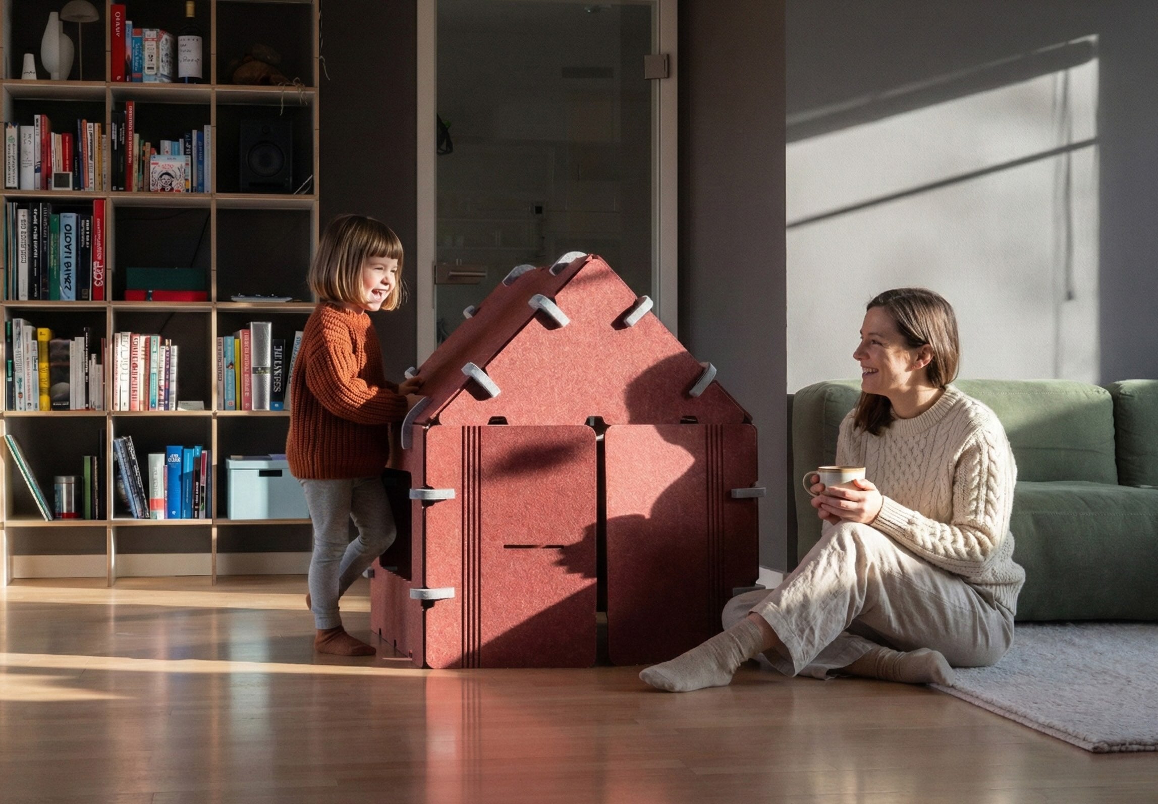 Design Indoor-Spielhaus aus Filz in Terrakotta. Mutter und Tochter lächeln sich an. Geräuschdämpfend, sicher und ästhetisch für das moderne Zuhause.