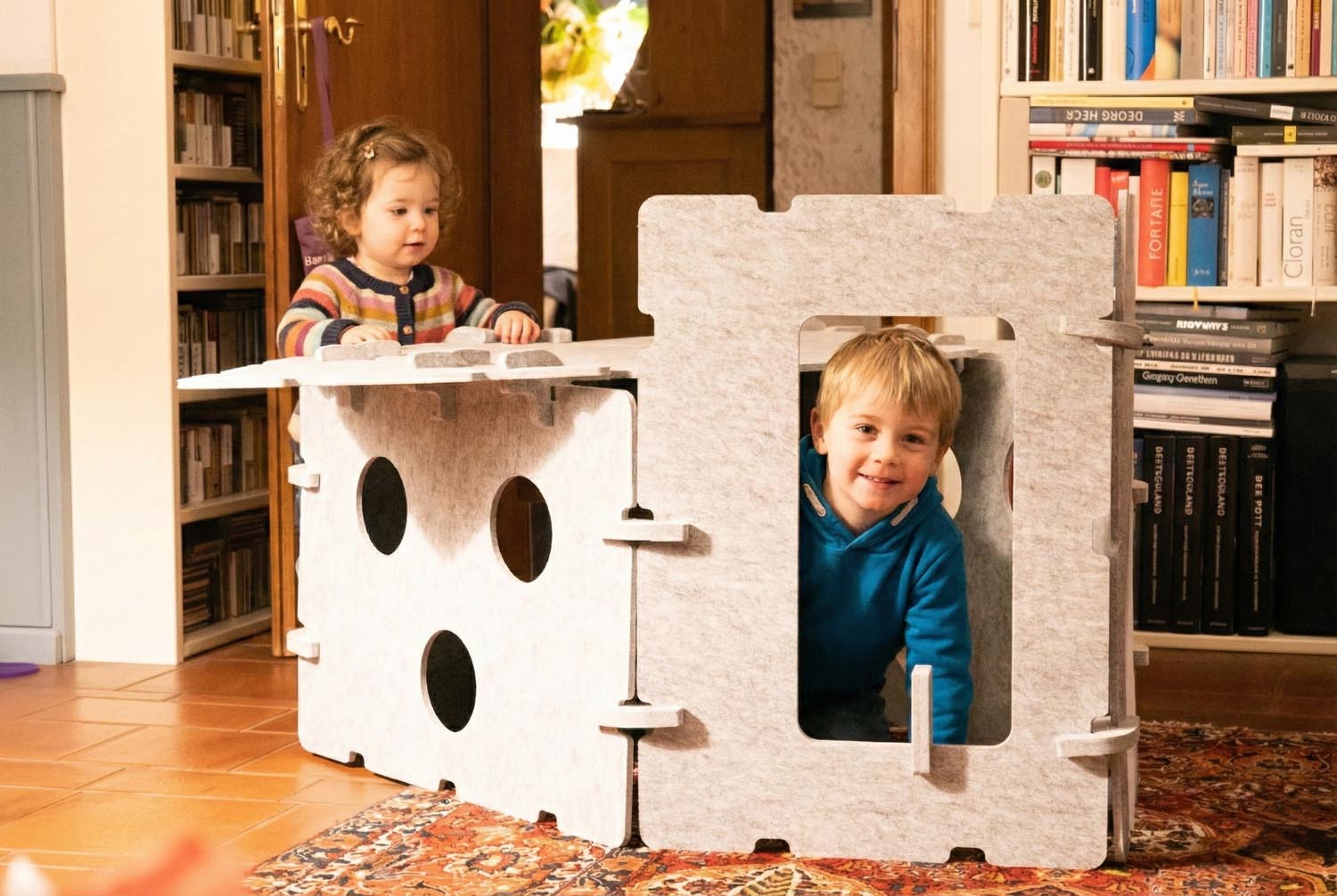 Kind schaut durch das Fenster des Spielhauses. Fantasievolles Versteckspiel und Rollenspiele.